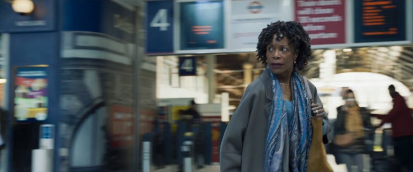 Priscilla walking through a London train station.