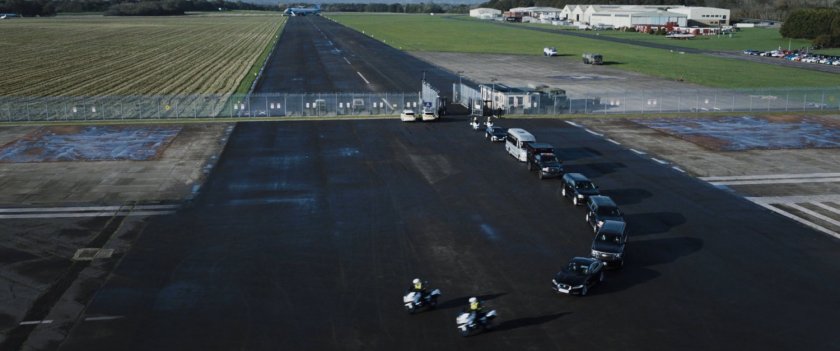 Aerial view of motorcade drives through the security entrance of the airfield.