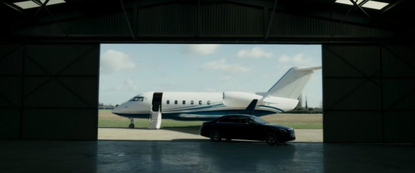 A small airplane and car framed inside aviation hangar opening.