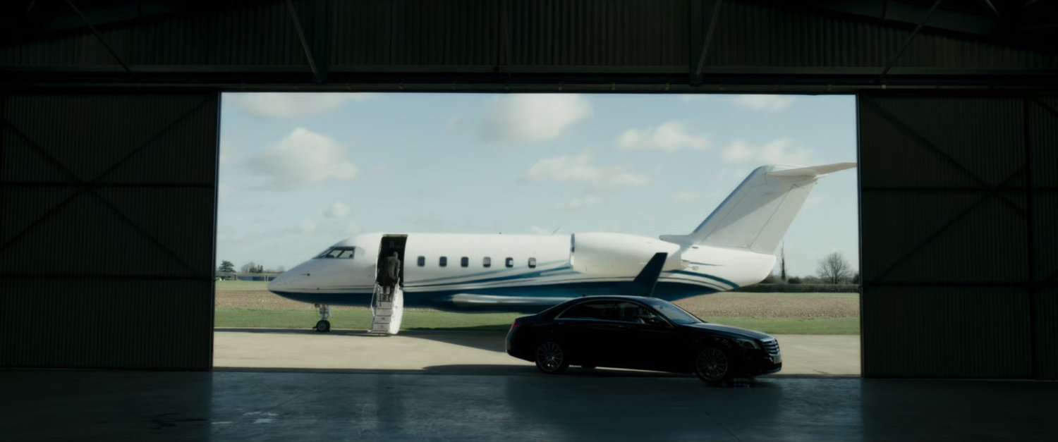 A small airplane and car framed inside aviation hangar opening.