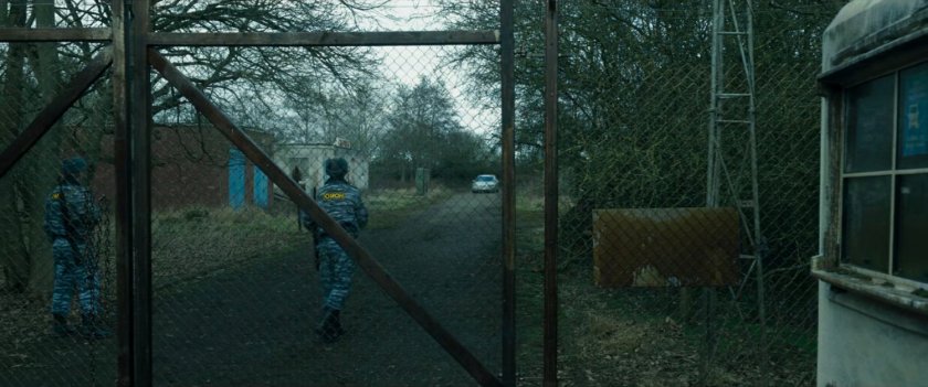 A car approaches the New Skrullos gate and guard post.