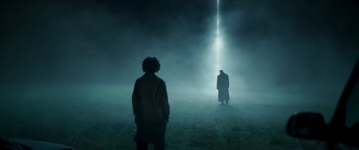 Fury and Priscilla stand in front of a beam of light in a clearing.
