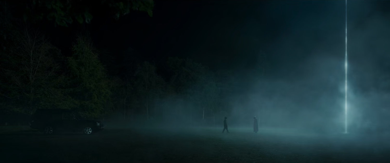 Fury and Priscilla stand in front of a beam of light in a clearing.