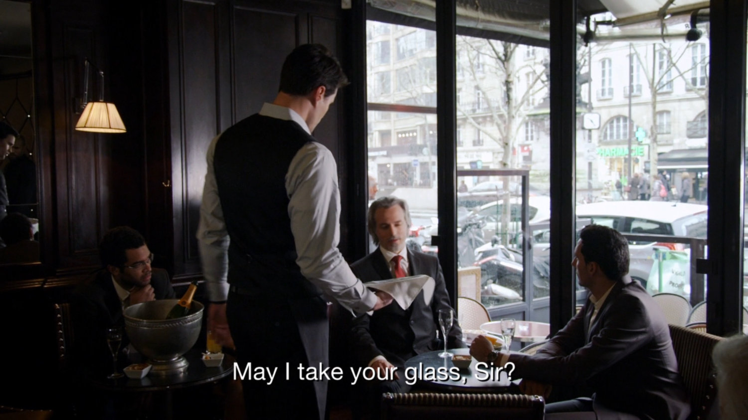 Grant Ward as a waiter in French restaurant. Text: May I take your glass, Sir?