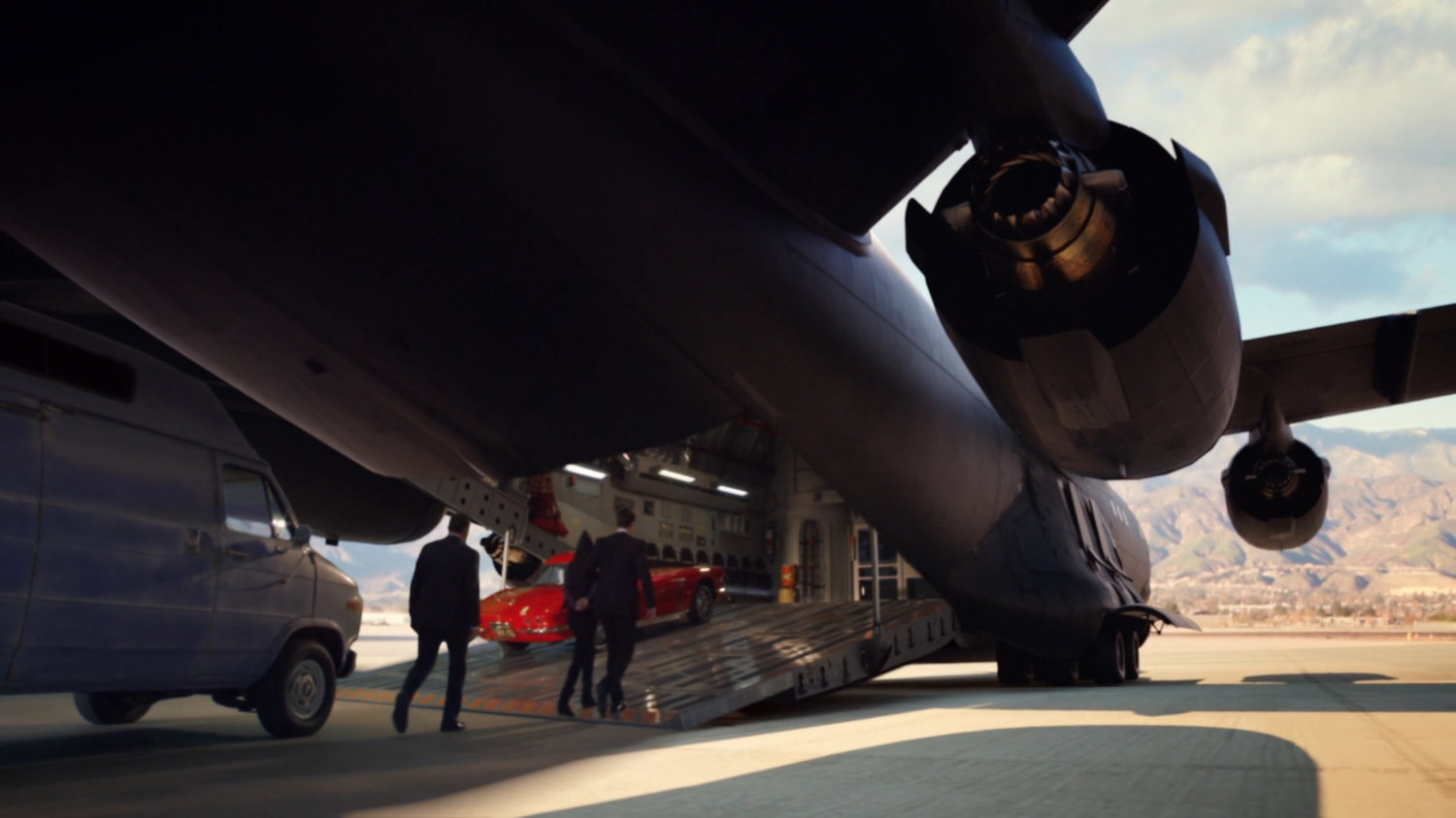 The Bus parked on tarmac and agents walking up rear ramp.