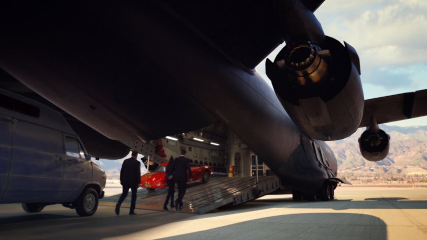 The Bus parked on tarmac and agents walking up rear ramp.