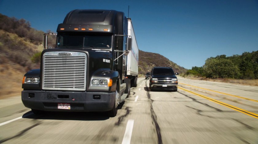 Semi truck on Colorado highway flanked by SUVs.