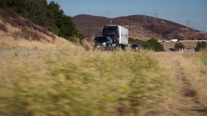 Semi truck on Colorado highway flanked by SUVs.