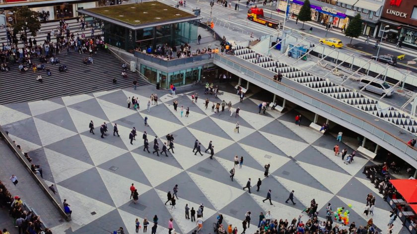 Aerial view of mysterious men in red masks walking across Sergel's Square.
