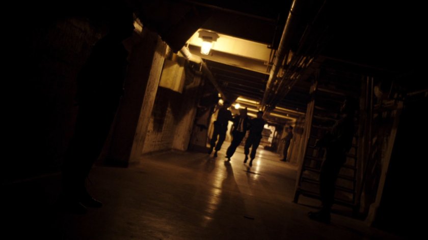 Three figures walking in a dark underground tunnel.