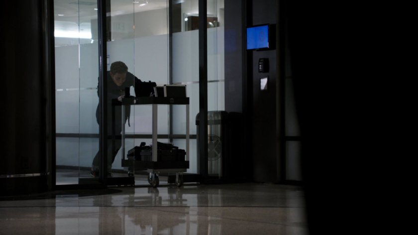 Fitz pushing a trolley through sliding glass doors in The Hub.