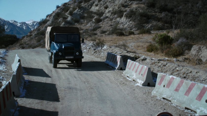 A covered truck approaches a Caucasus Mountain checkpoint.