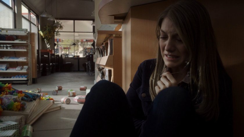 Hannah Hutchins cowers under a convenience store counter.