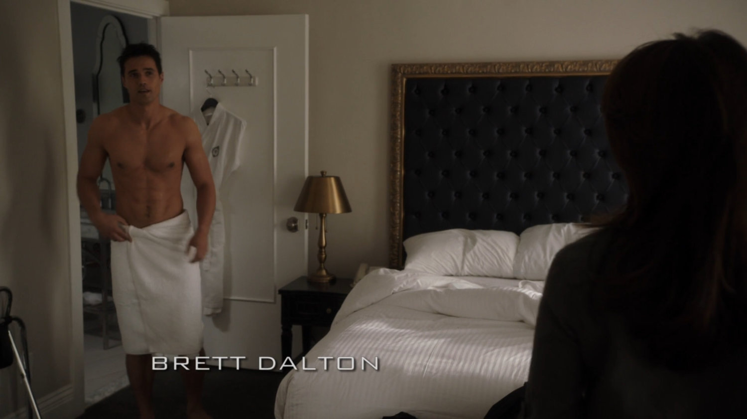 Ward, wearing only a towel, exits the bathroom in an Irish hotel room.