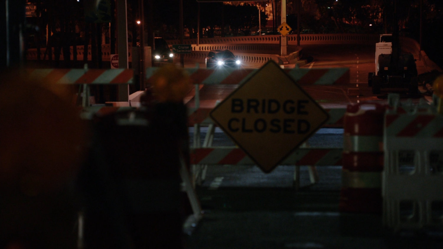 A car approaches barricades with "Bridge Closed" sign.