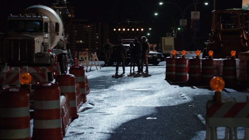 A small group of people stand on an under construction bridge at nighttime.