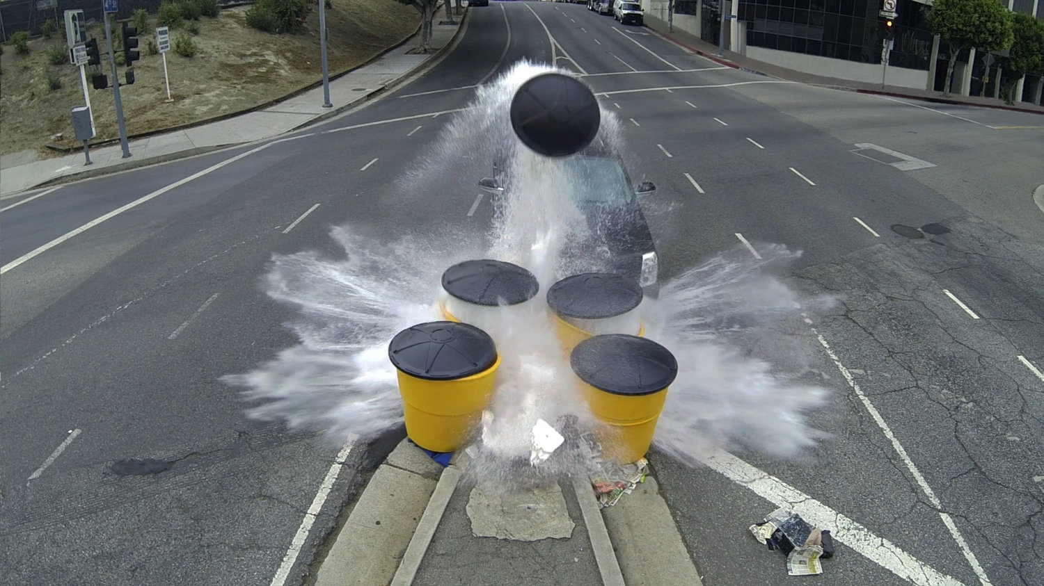 Black SUV crashing into water barrels in Los Angeles intersection.
