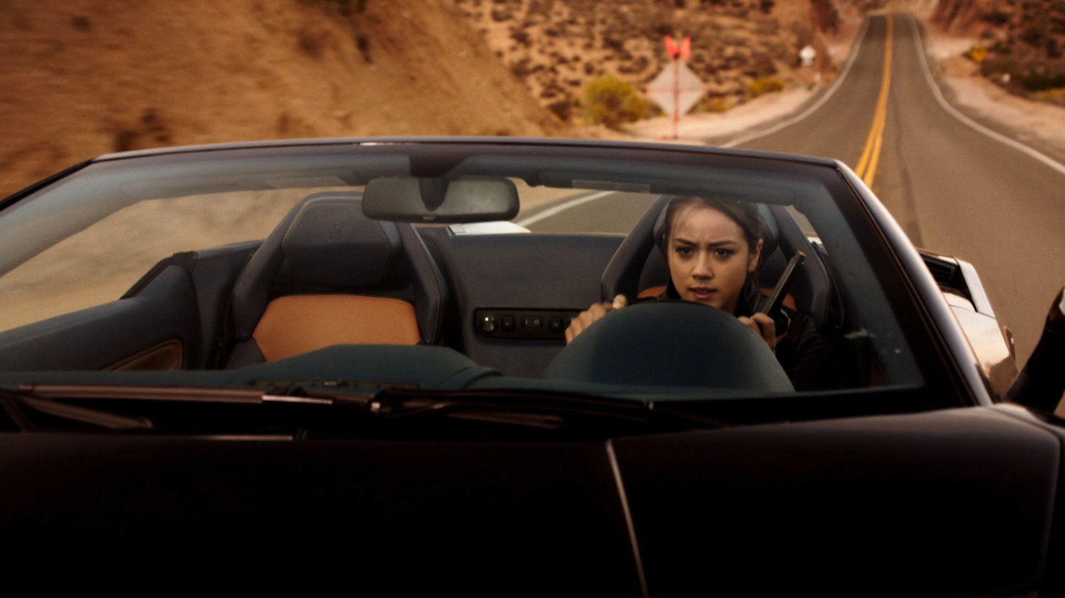 Skye in a sports car on desert road.