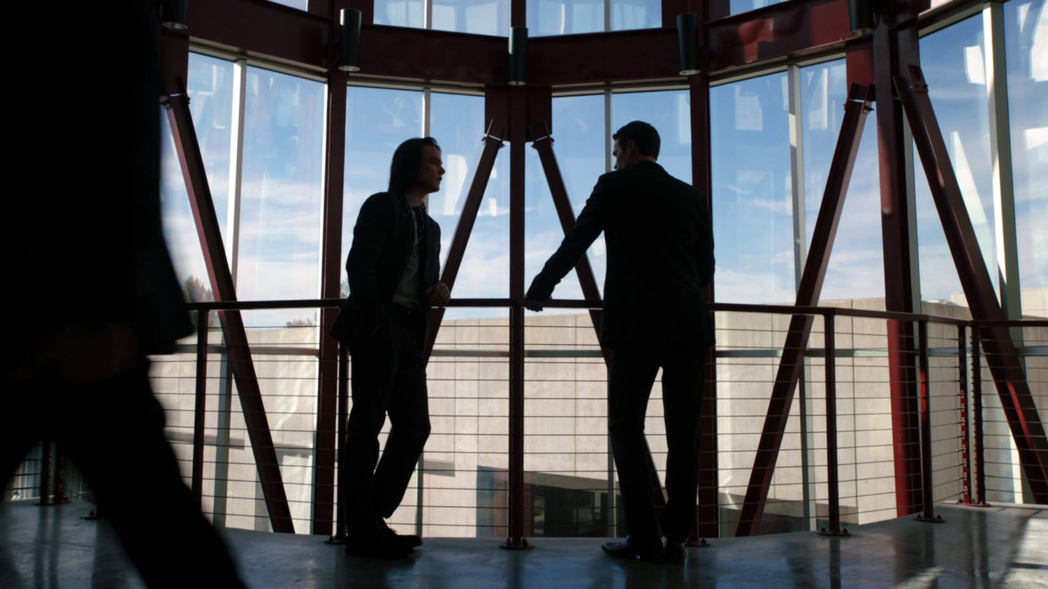 Ward and Seth talk in a small glass atrium looking onto the roof of a nearby building.