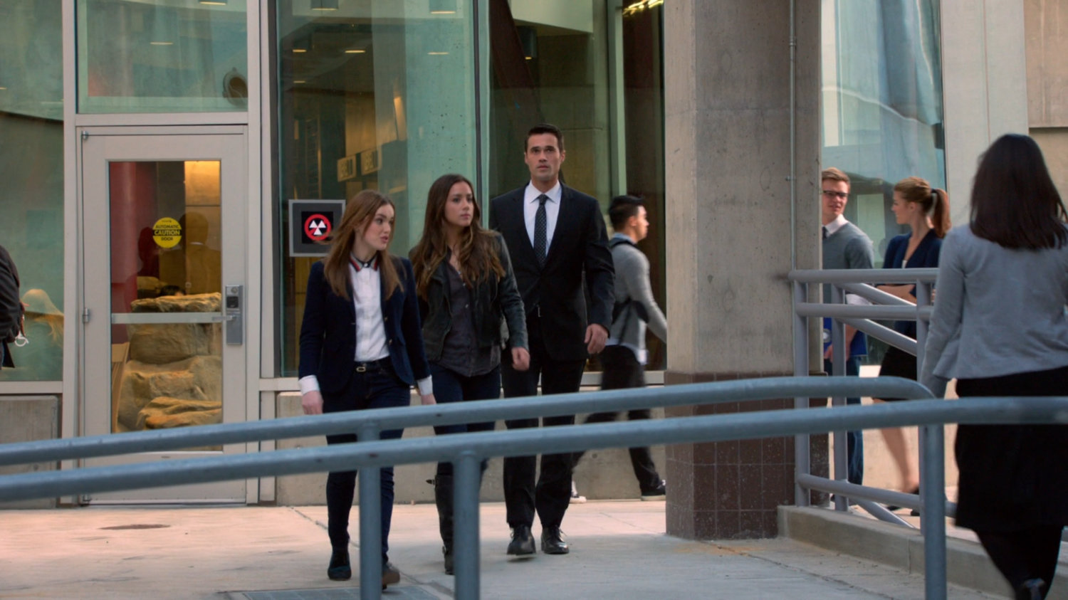 Ward, Skye, and Simmons walking through SHIELD academy walkway by large window.