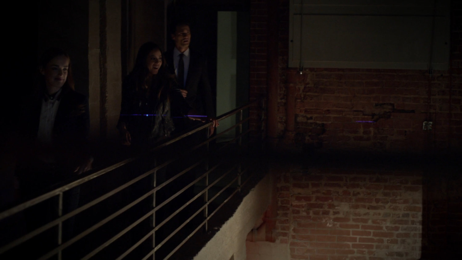 Ward, Skye, and Simmons on dark walkway by brick wall.