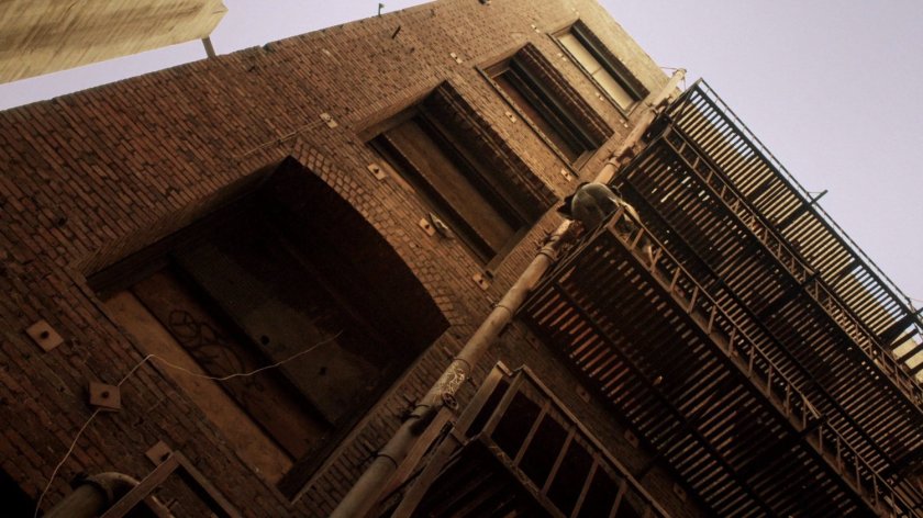 Agent Lumley climbs a fire escape in the alley.