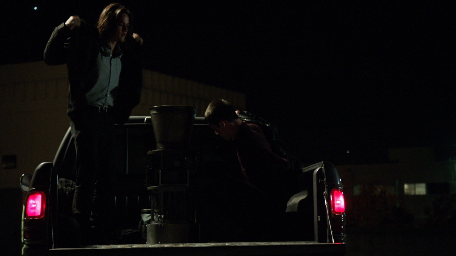 Seth and Donnie in a pickup truck on a parking deck.
