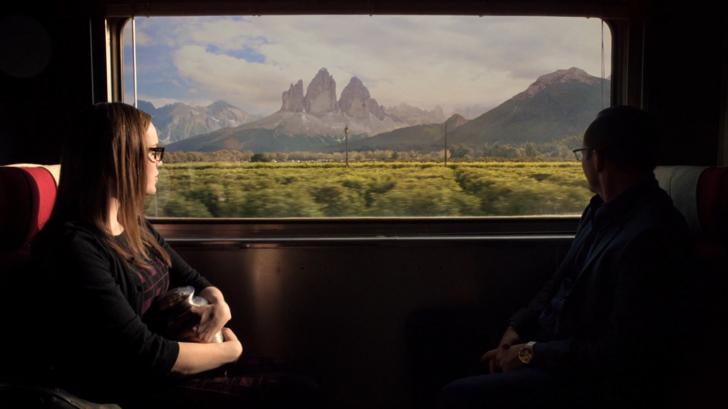 Simmons and Coulson look at the Tre Cime di Lavaredo mountains outside the train.
