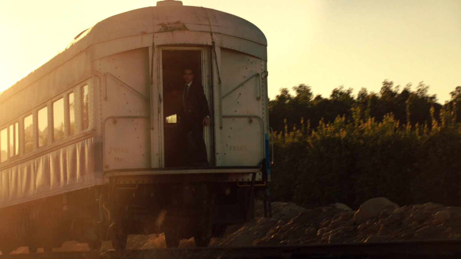 A man standing on the back of a train.