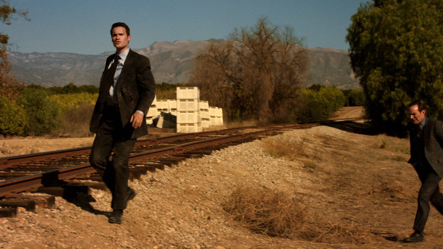 Ward and Coulson walking near train tracks.