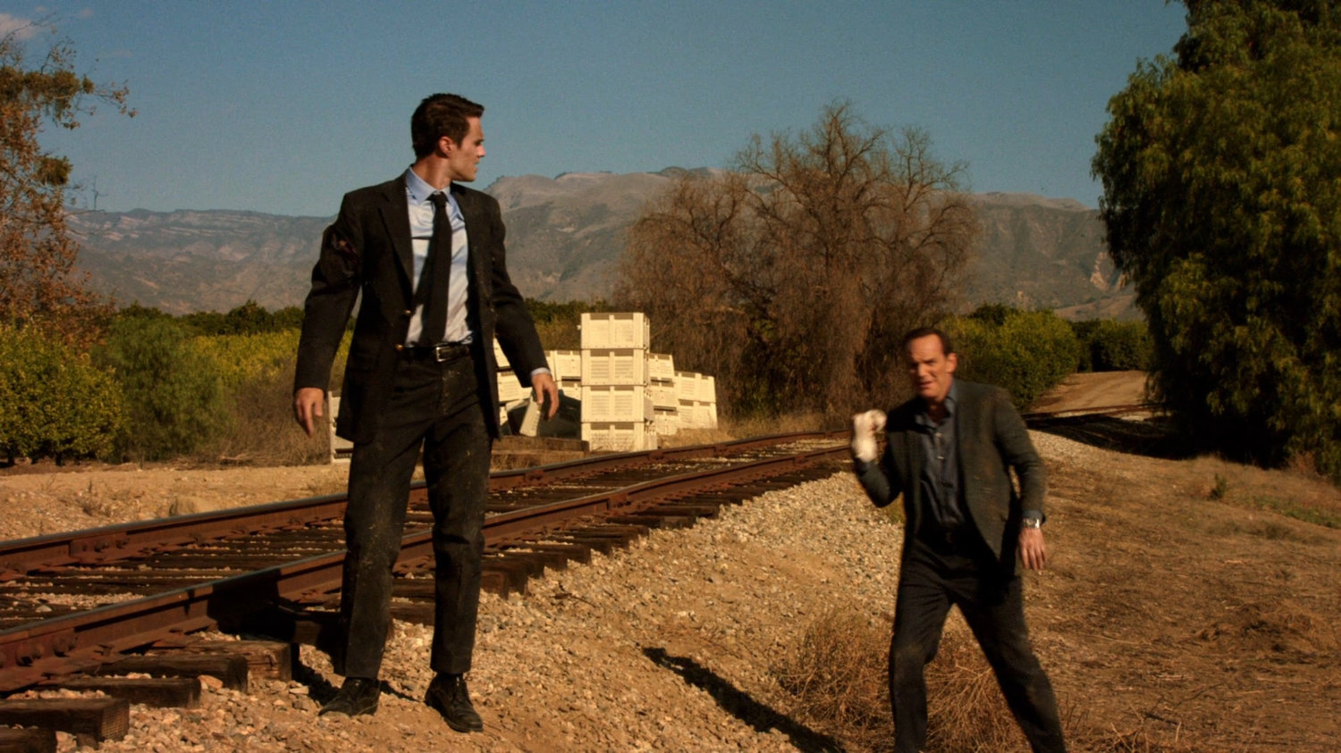 Ward and Coulson walking near train tracks.