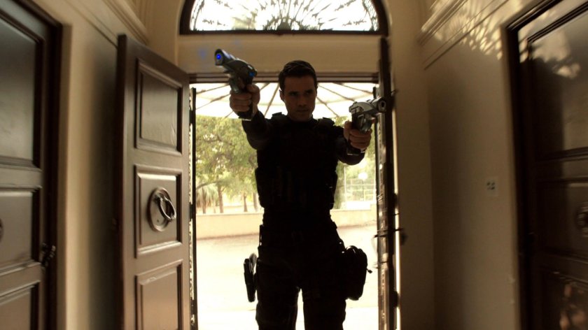 Agent Ward with guns drawn entering front door of Italian villa.