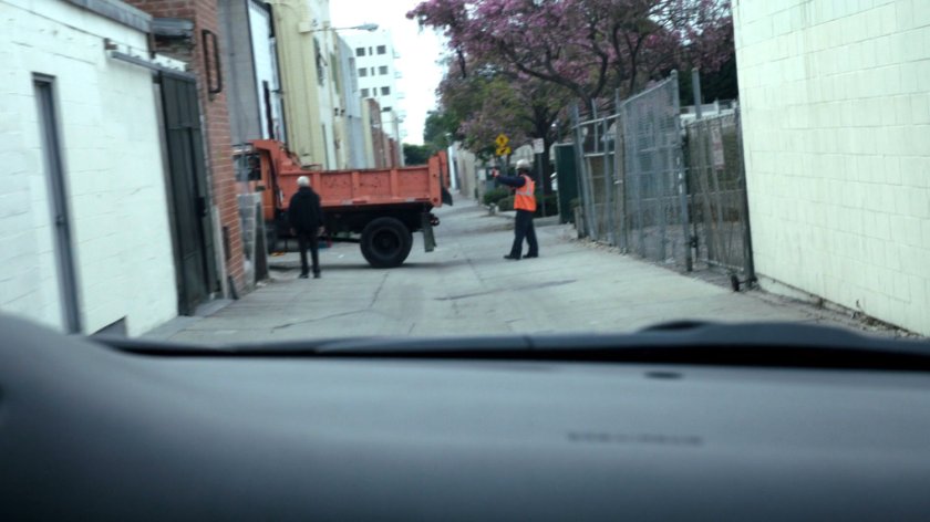POV from inside vehicle in an alley approaching a construction dump truck.