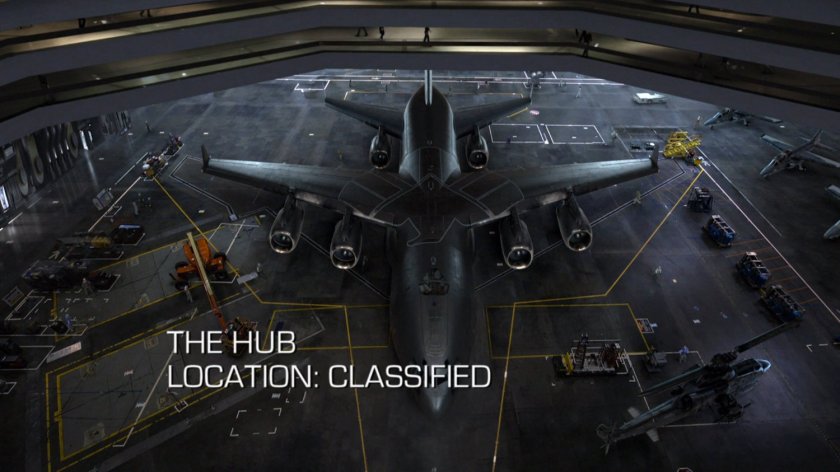 The Bus parked in an interior hangar. Text: The Hub, Location: Classified.