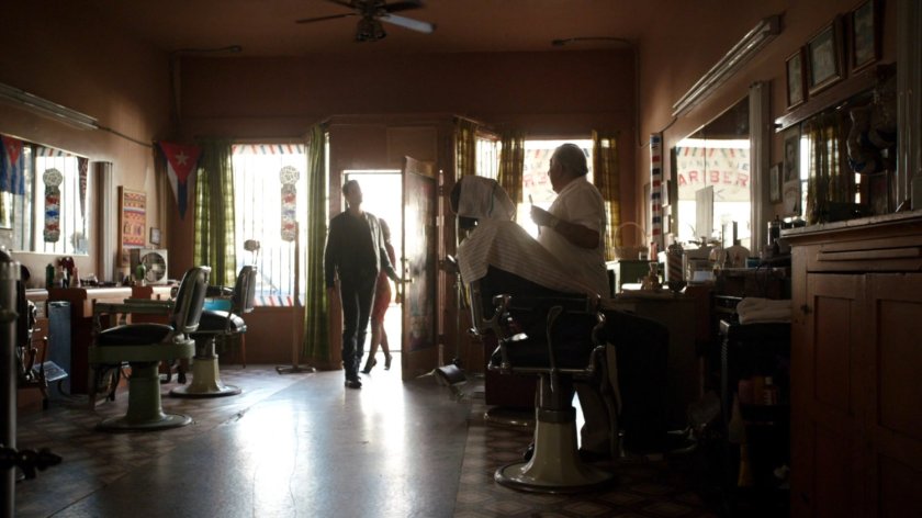 Ward and Raina enter a Cuban barber shop.