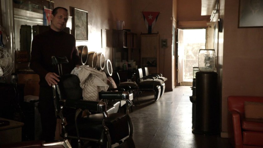 Garrett offers a chair in a Cuban barber shop.