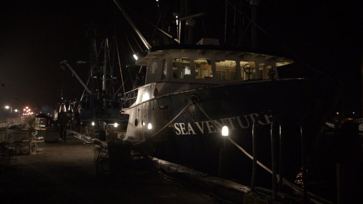Nighttime view of dock next to boat named Sea Venture.