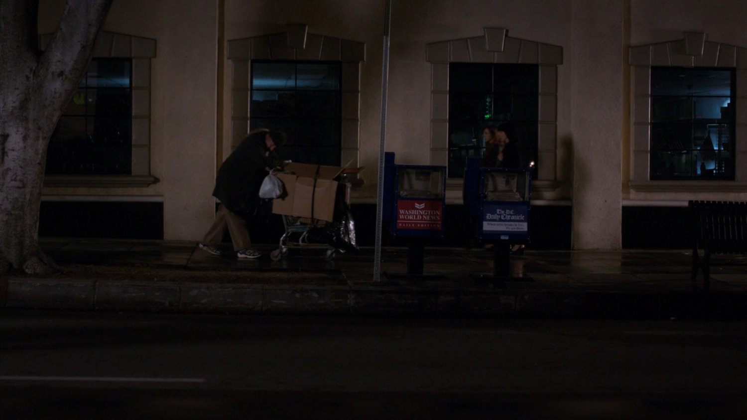 A homeless man pushing a grocery cart on the sidewalk in Washington DC.