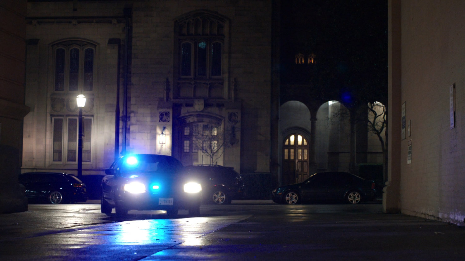 A police car enters a dark alley across from a church in Washington DC.