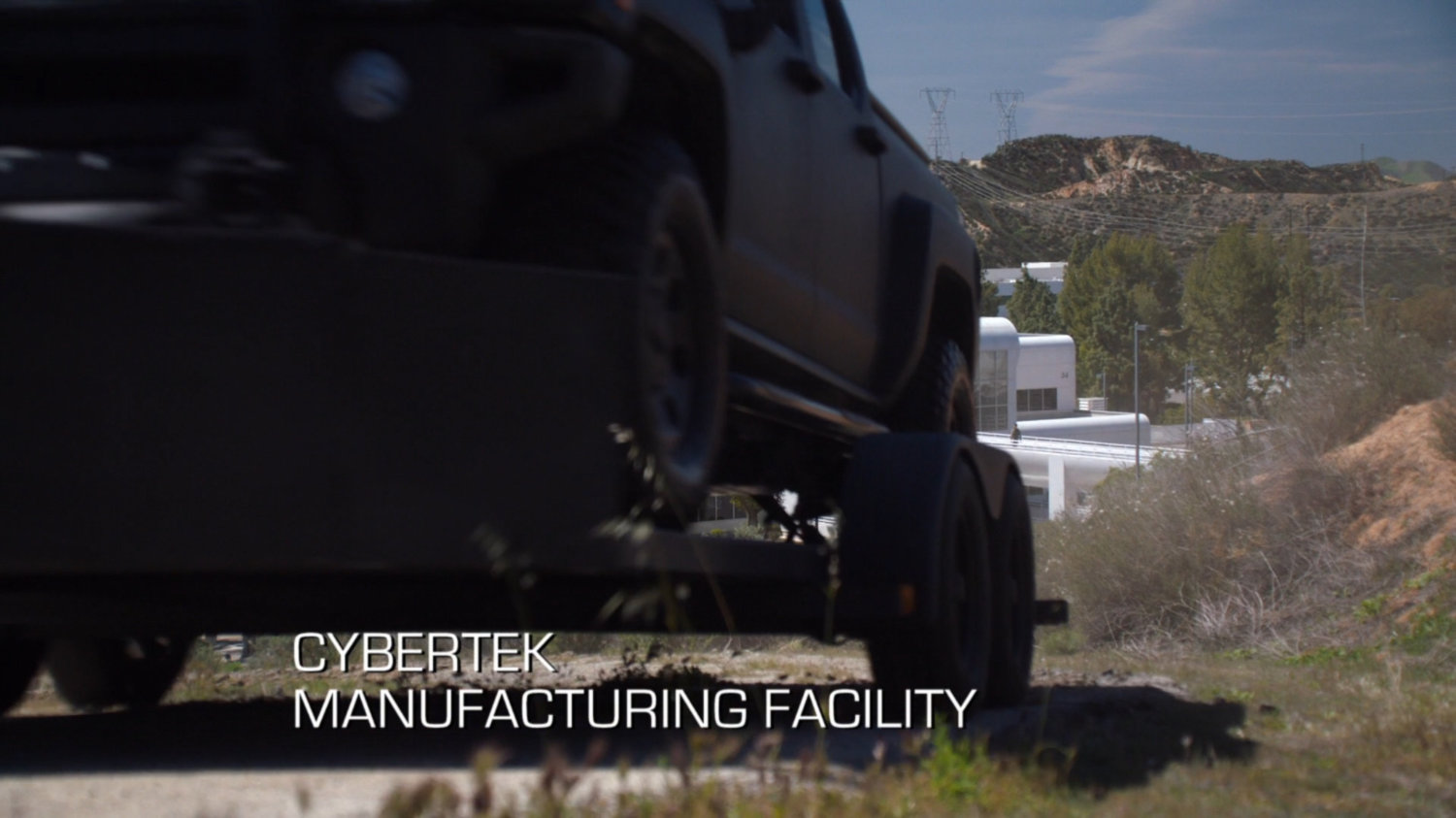 A truck on a hilly road outside Cybertek offices. Text: Cybertek Manufacturing Facility.
