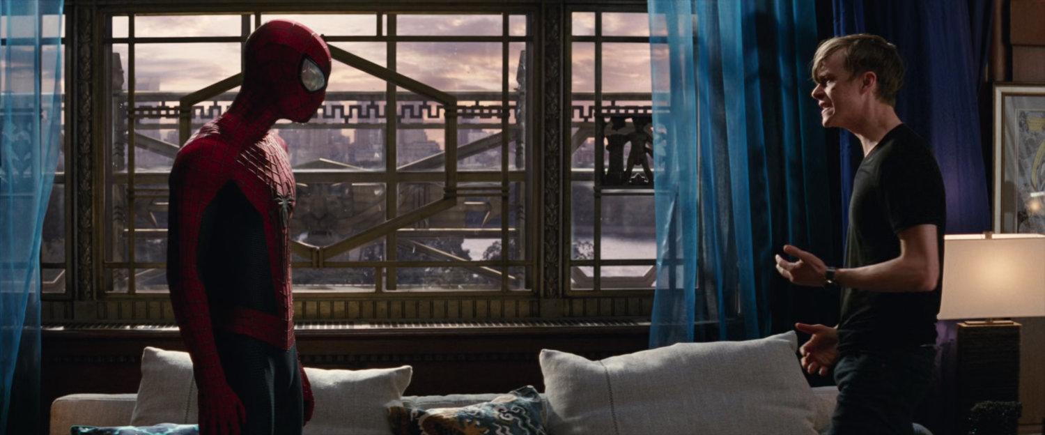 Spider-Man and Harry in his apartment by a large window.