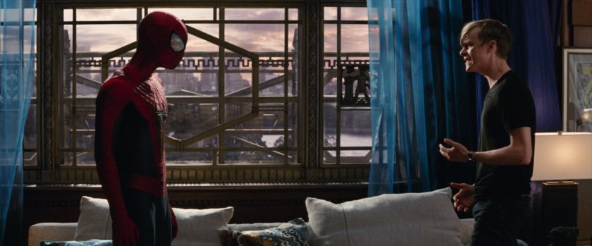 Spider-Man and Harry in his apartment by a large window.