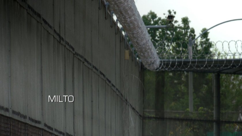 Ward and Triplett walk by a large chain link fence.