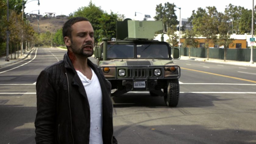 Hunter stands in street as humvee approaches.
