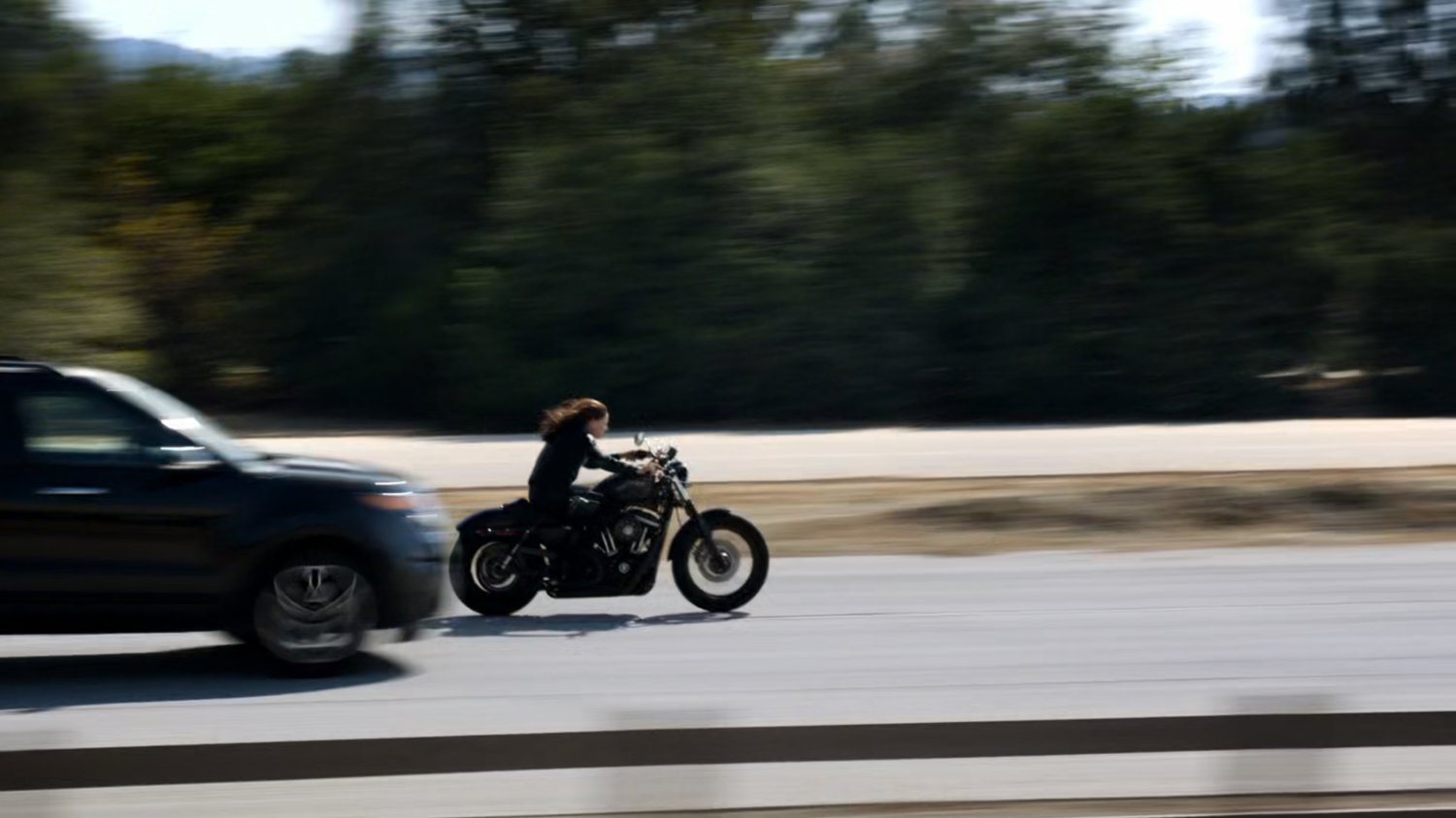 Agent May racing along a busy road on a motorcycle.
