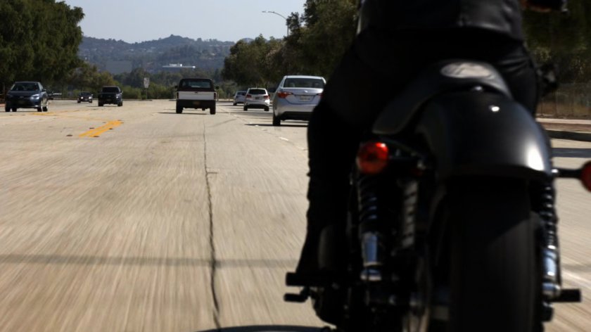 Agent May racing along a busy road on a motorcycle towards a pickup truck.