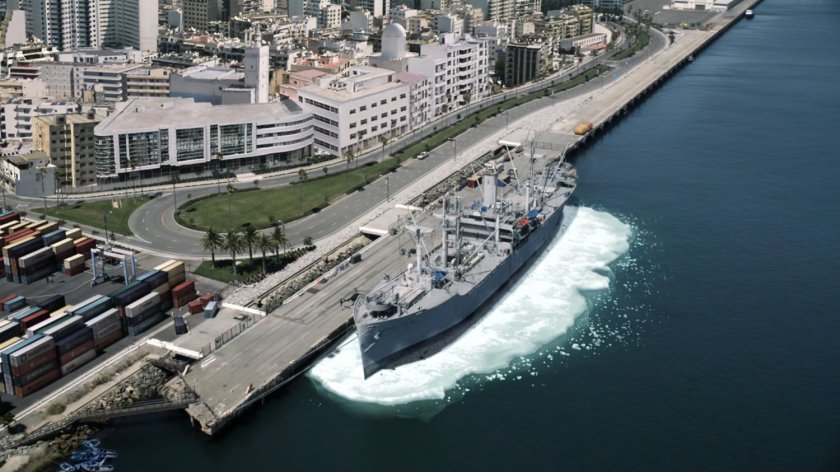 A ship docked at pier with ice around its water line.