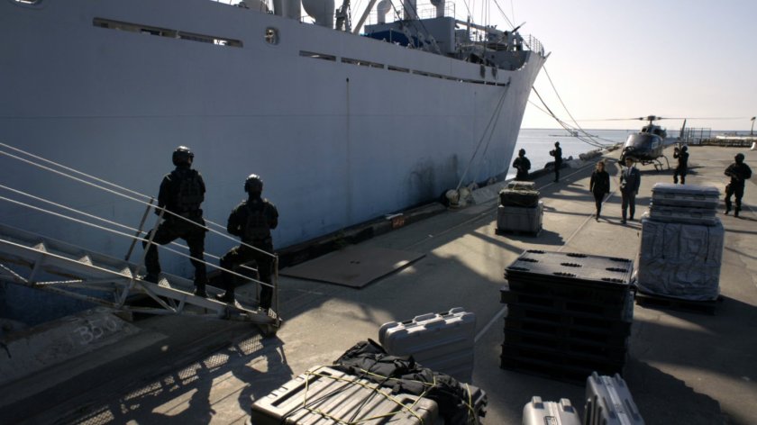 Soldiers on the dock next to a ship.