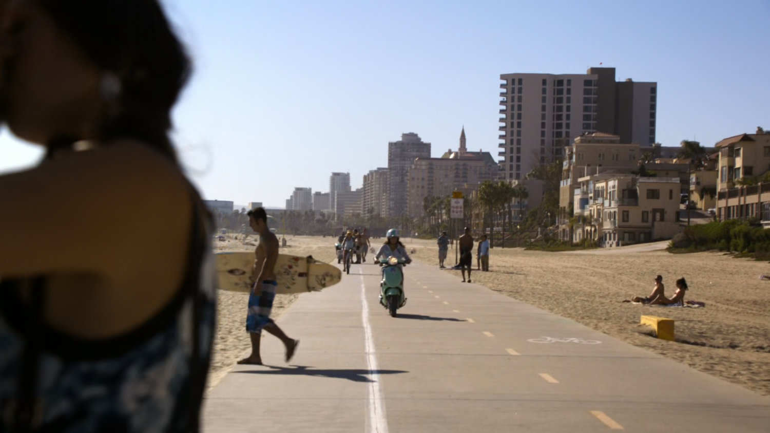 A scooter drives towards pedestrians on Florida beach boardwalk.