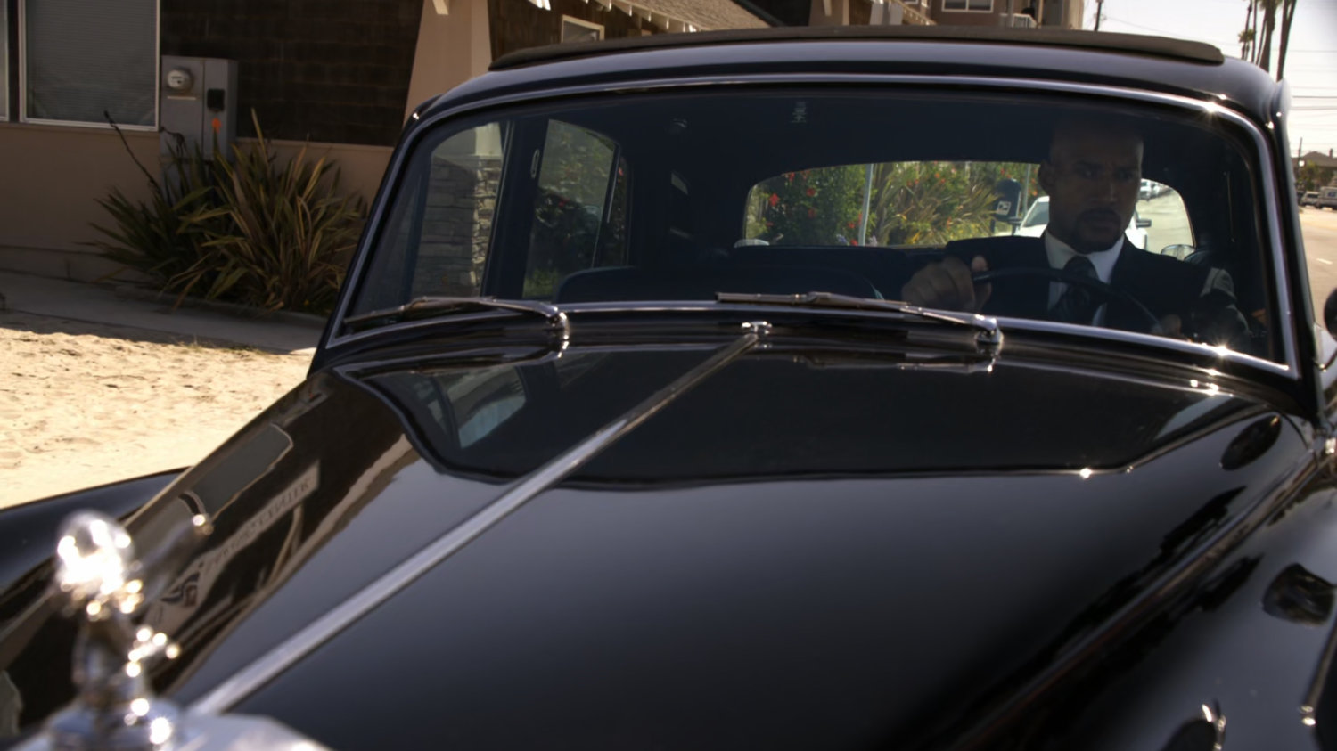 Mack in black Rolls Royce parking next to beach.